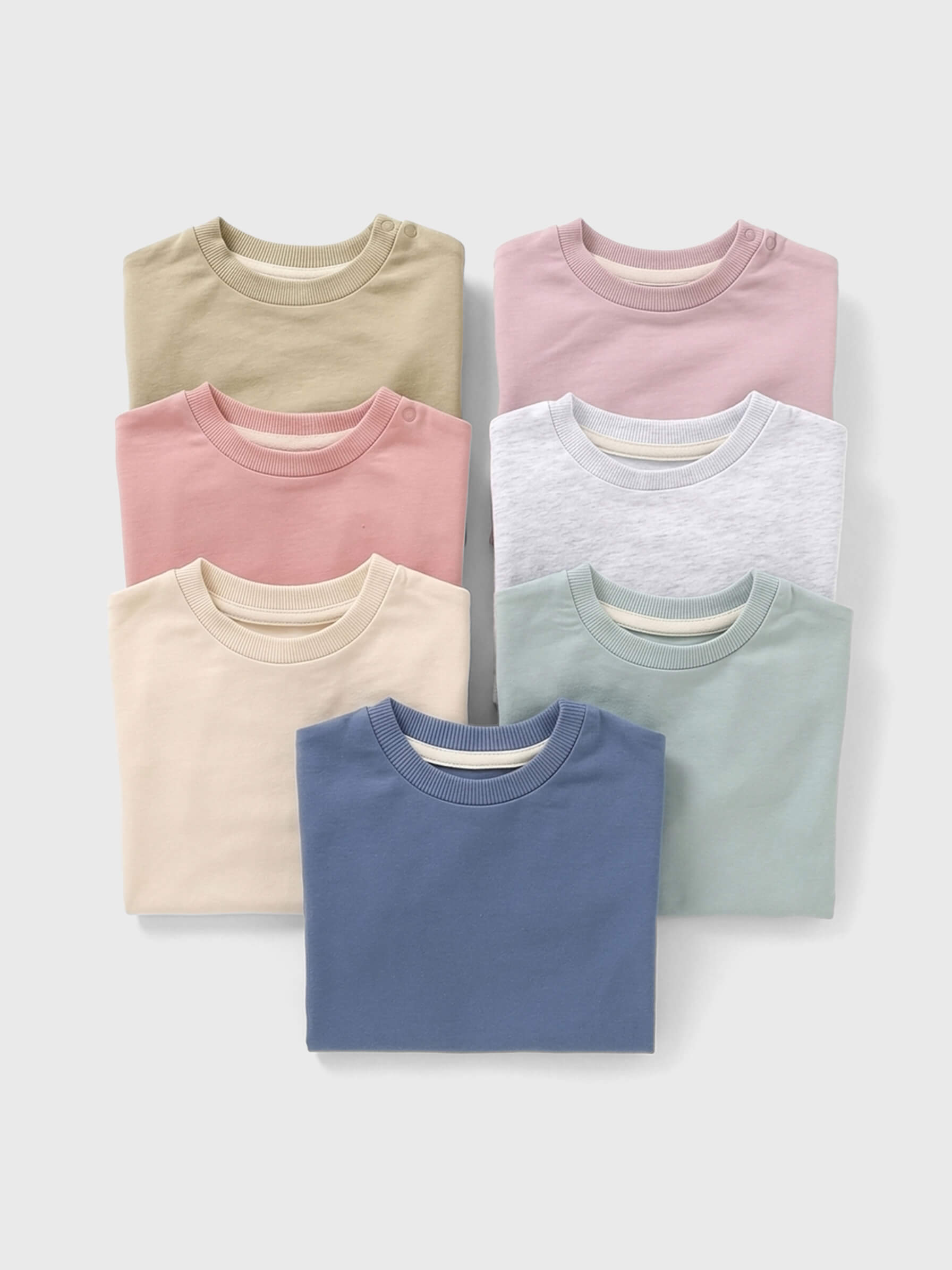 Stack of folded rompers in various pastel colors on a white background