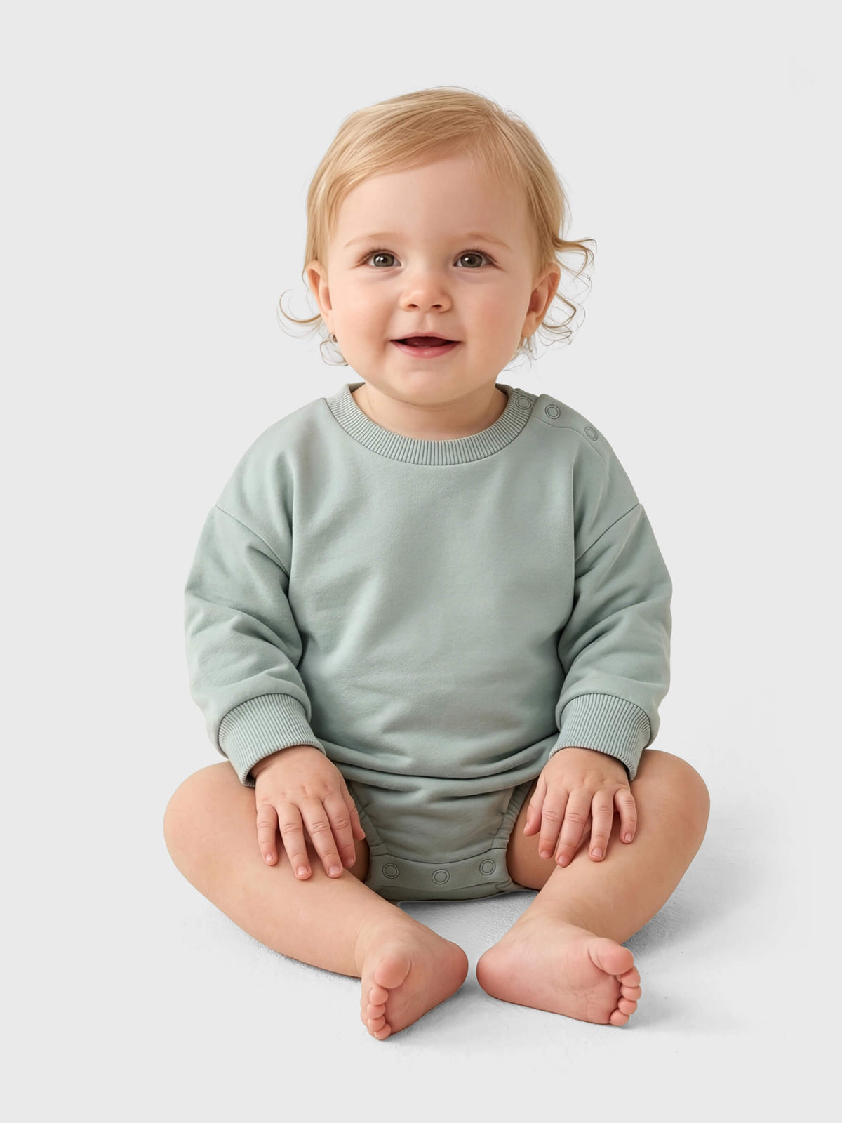 Baby wearing a soft olive sweater sitting on a white background