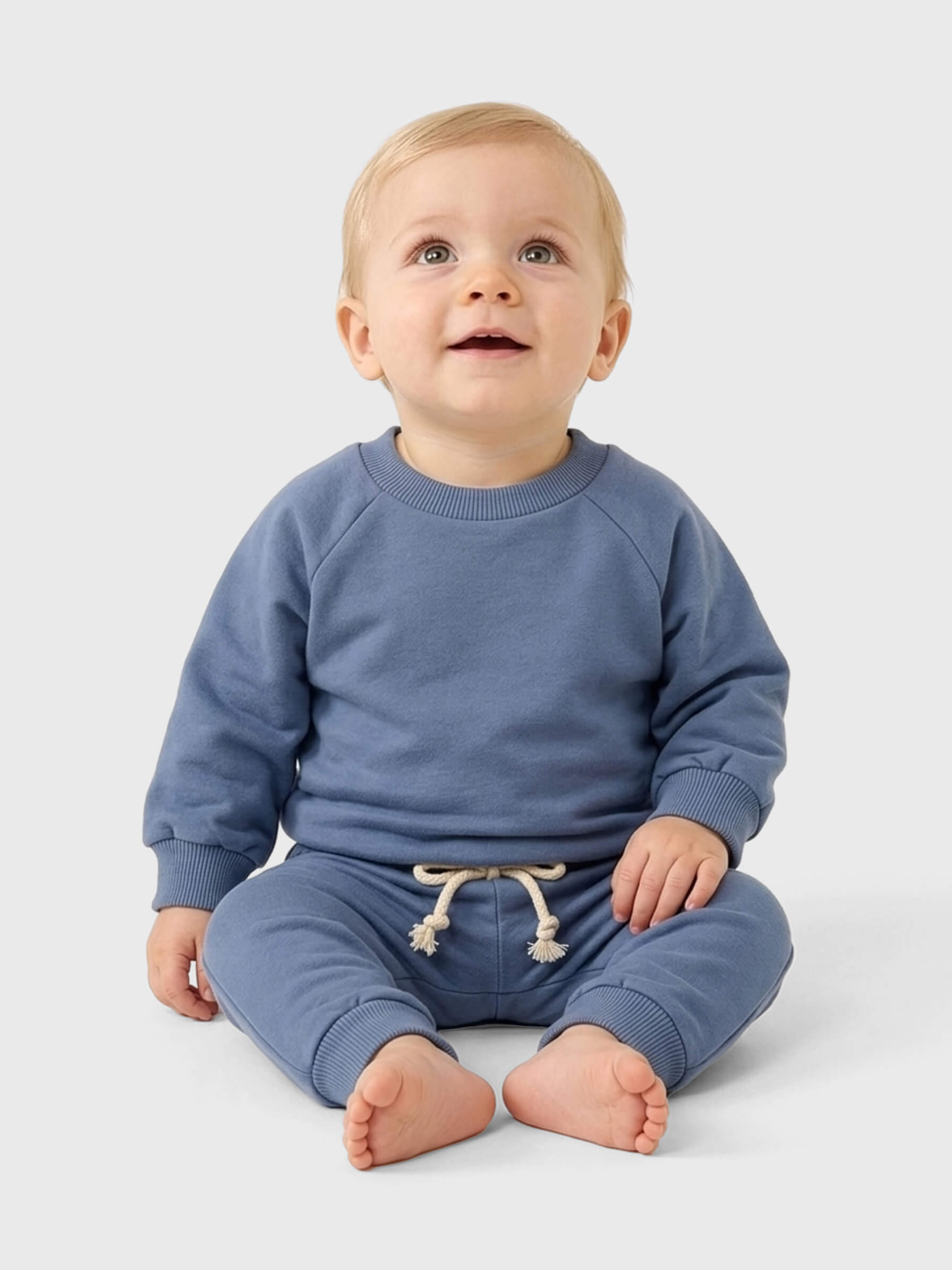 Baby wearing a blue outfit sitting on a white background