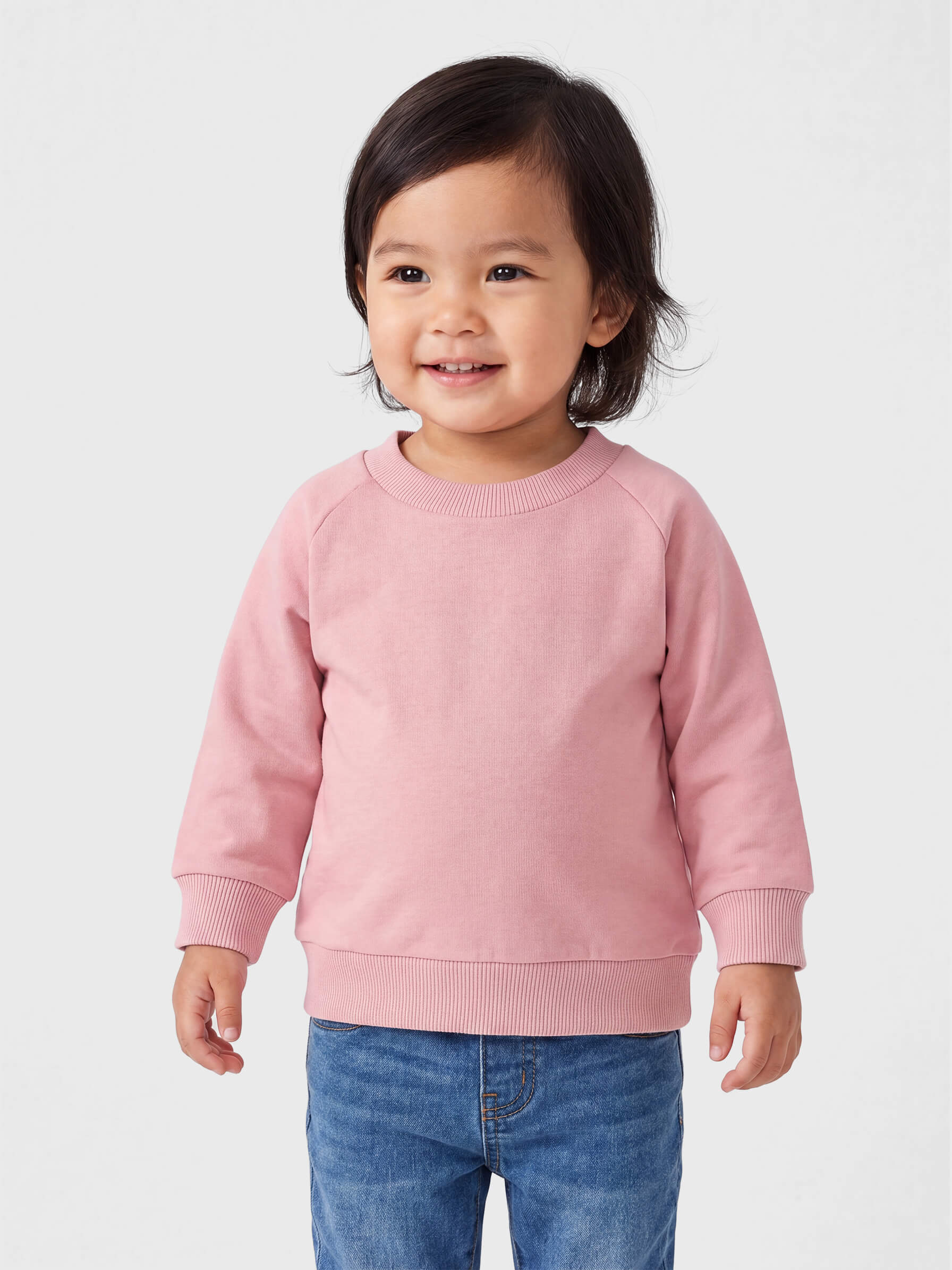 Child wearing a pink sweatshirt and blue jeans on a white background